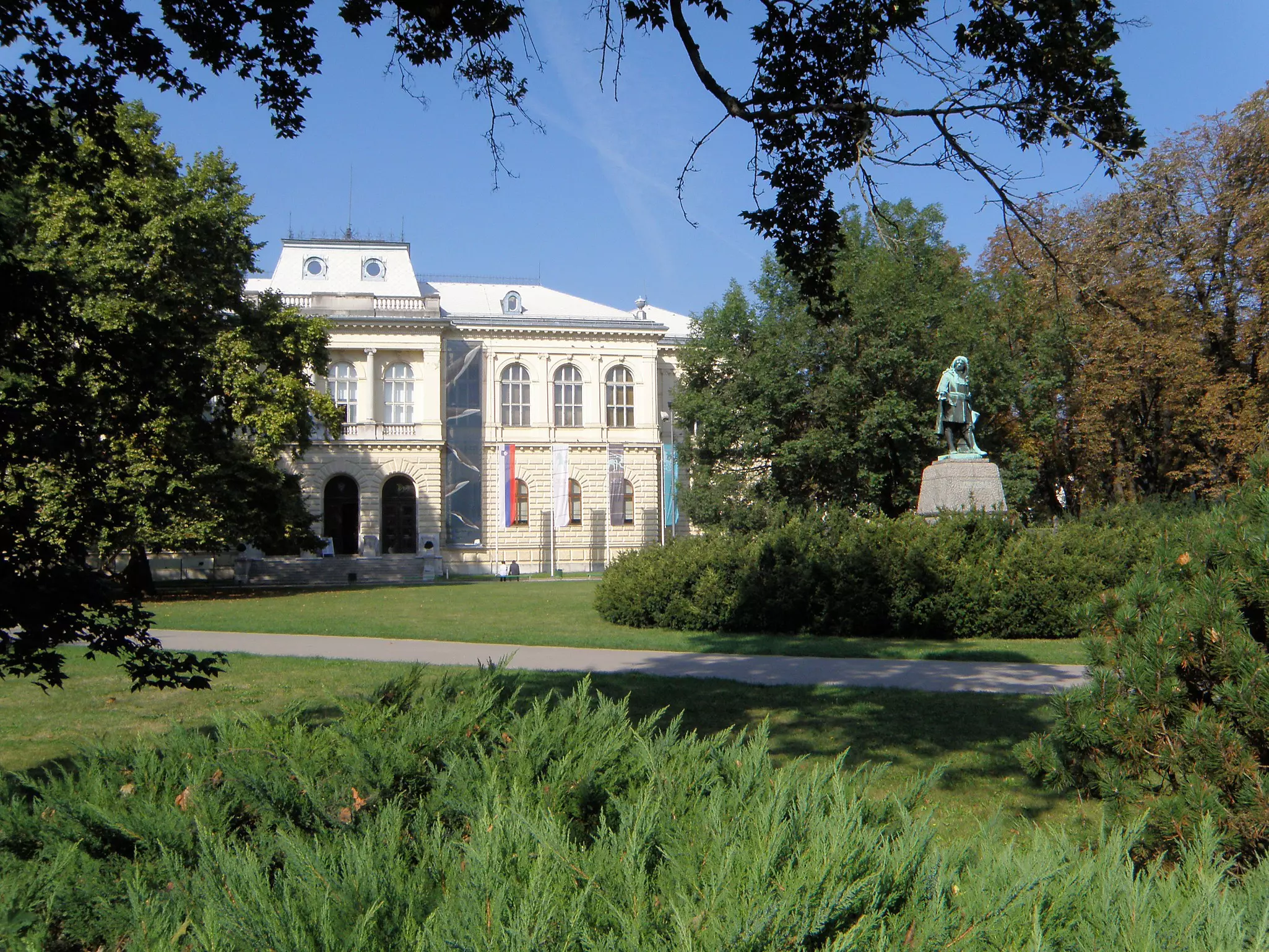 A white-brick museum building located in a lush garden