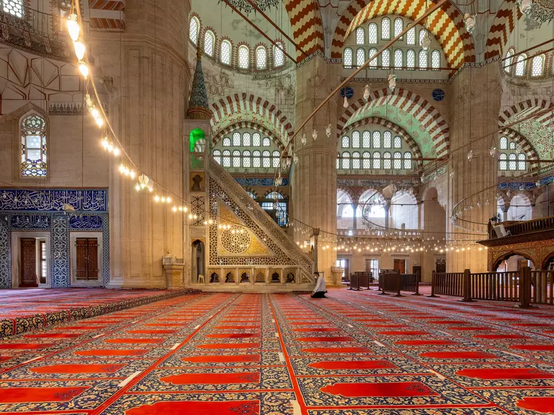 A man prays in an ornate Turkish mosque.  