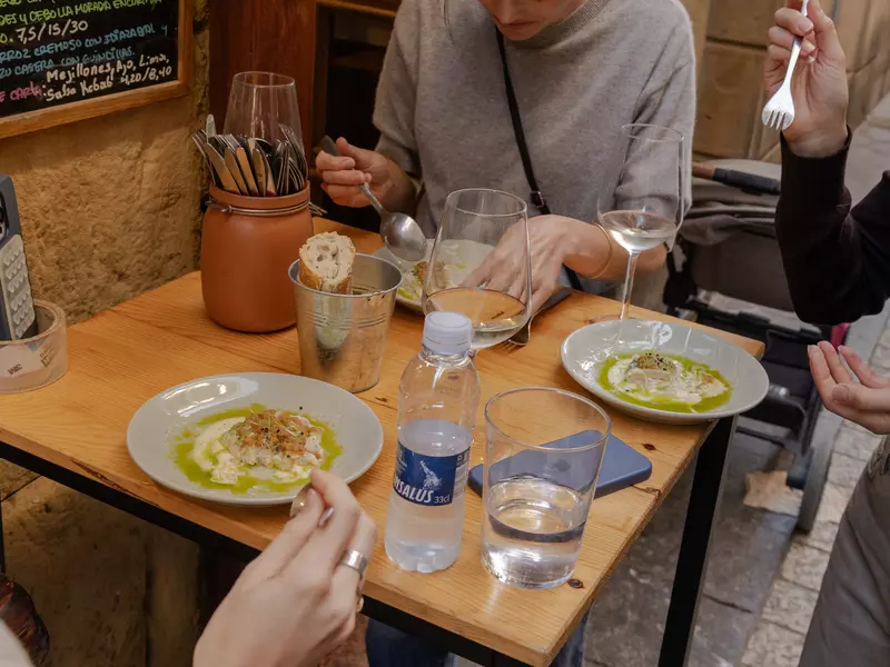 Small plates of food on a small square table.