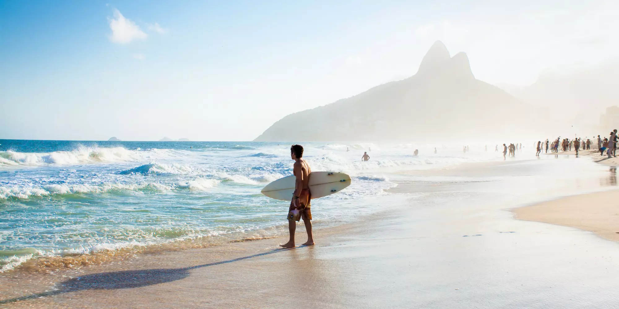 RIO DE JANEIRO, BRAZIL - APRIL 24, 2015: Brazilian surfer walking with surfboard toward Two Brothers Mountain at Ipanema Beach on April 24, 2015 at Copacabana Beach, Rio de Janeiro. Brazil.