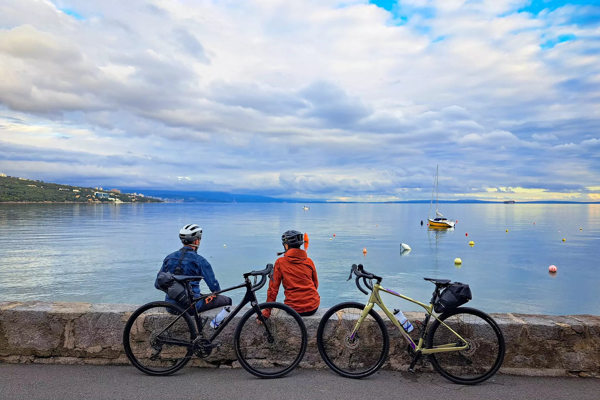 Two cyclists pause for a break beside a vast lake.