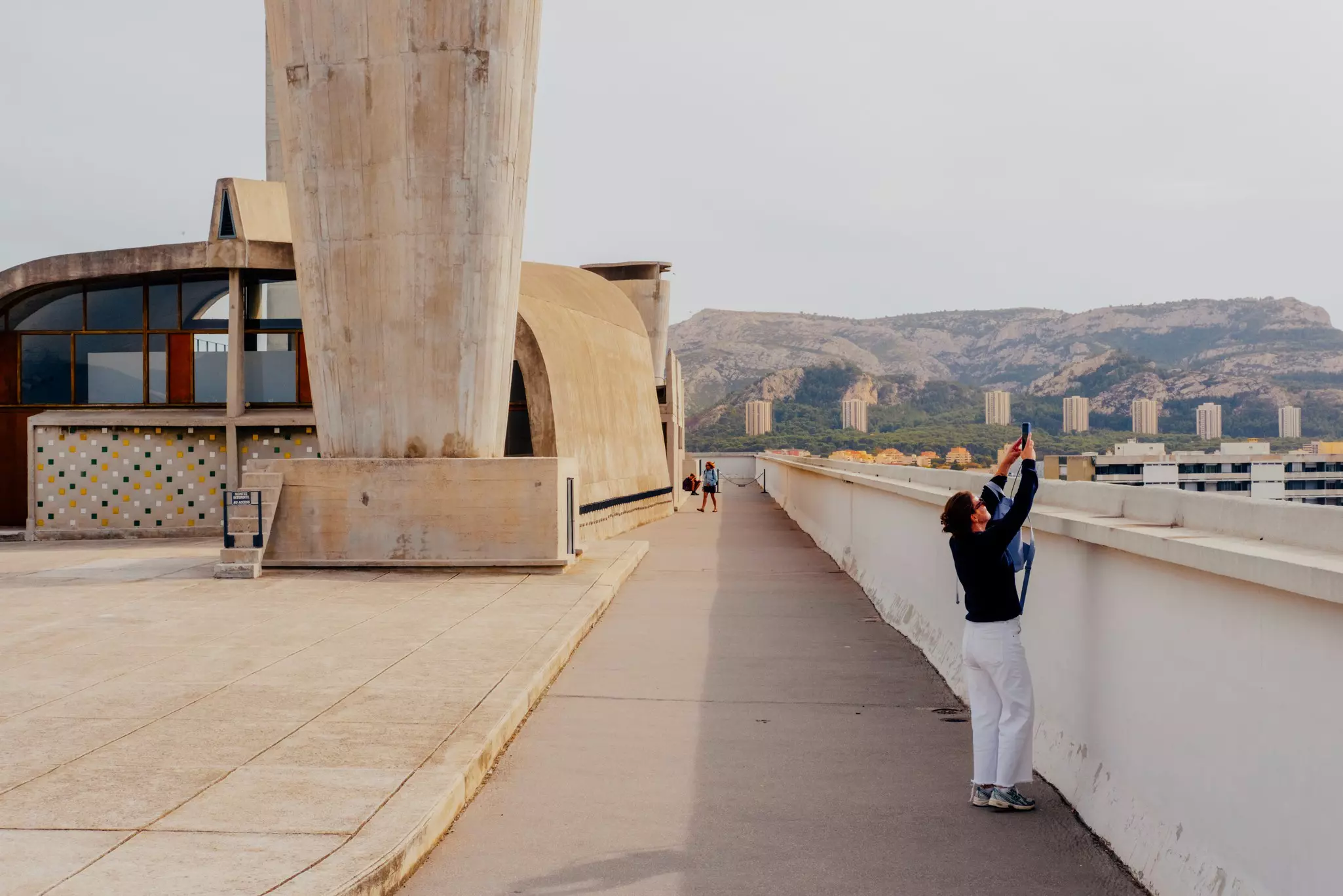 A woman takes a picture on the roof of a modern apartment building.