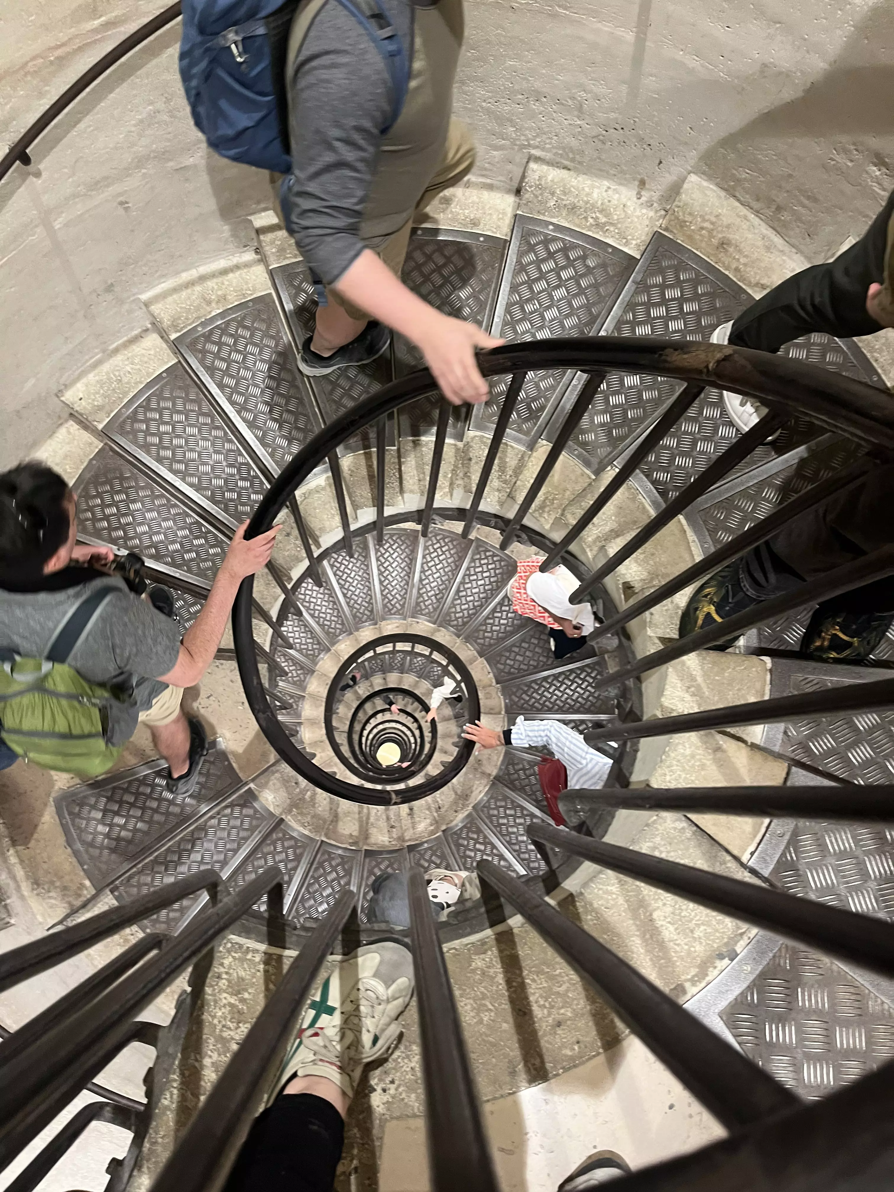 A tight spiral staircase. People walk up holding on tight to the handrail.