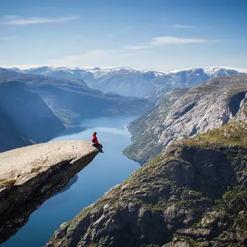 Man sitting on Trolltunga rock above a Norwegian fjord.