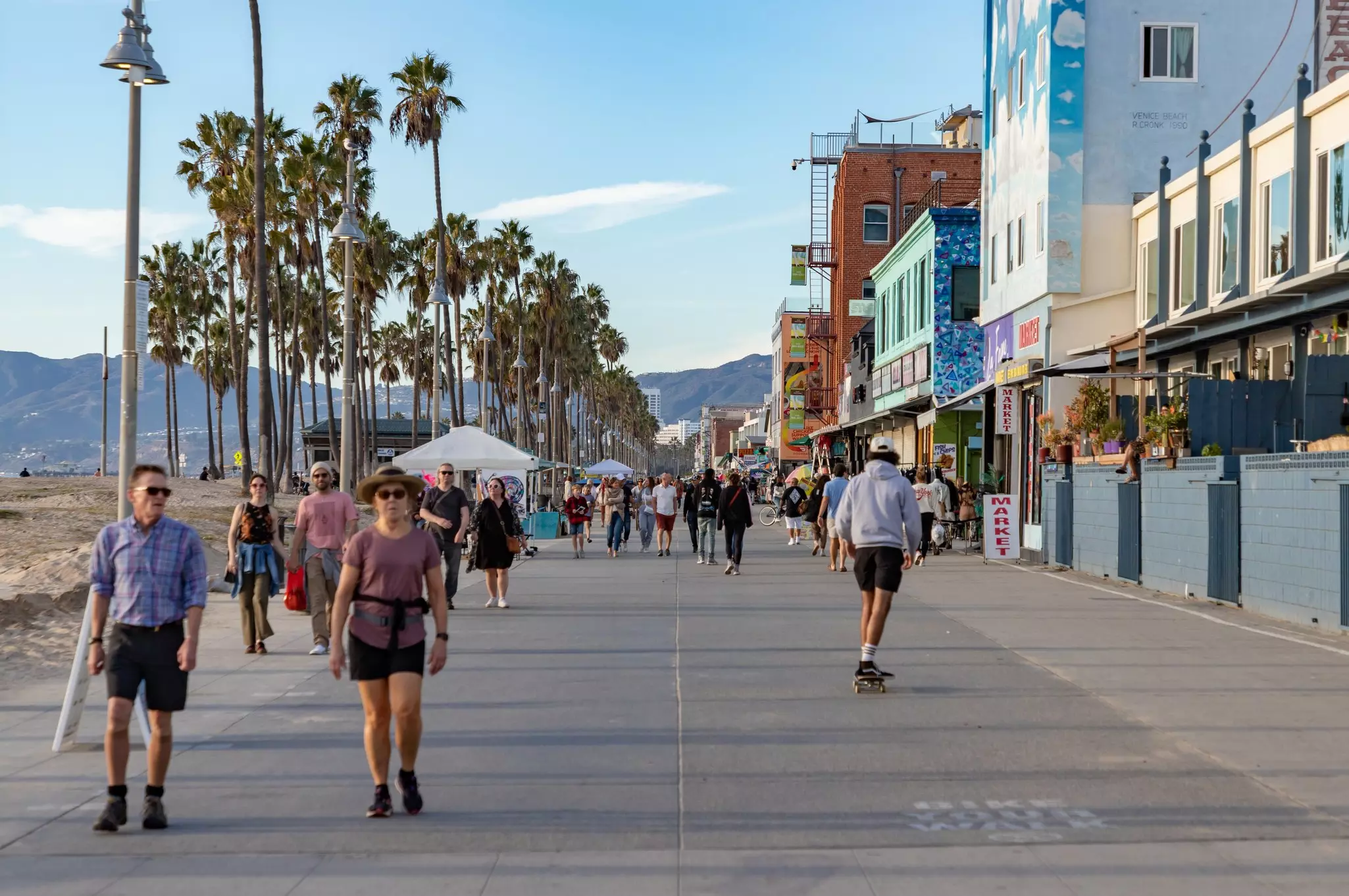 Los Angeles, United States: A picture of the iconic Venice Beach boardwalk with people walking and skateboarding on it.