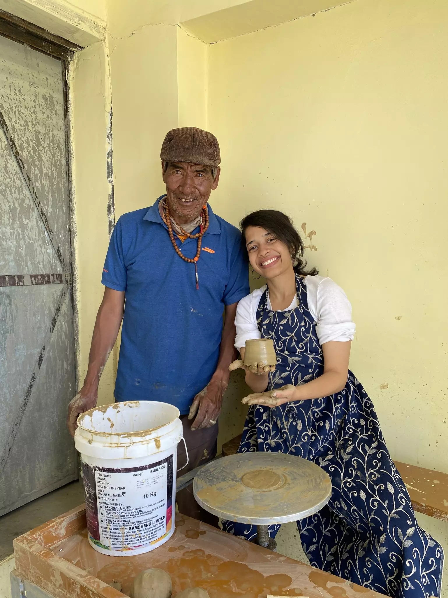 A man and a woman showing a cup made on a pottery wheel.
