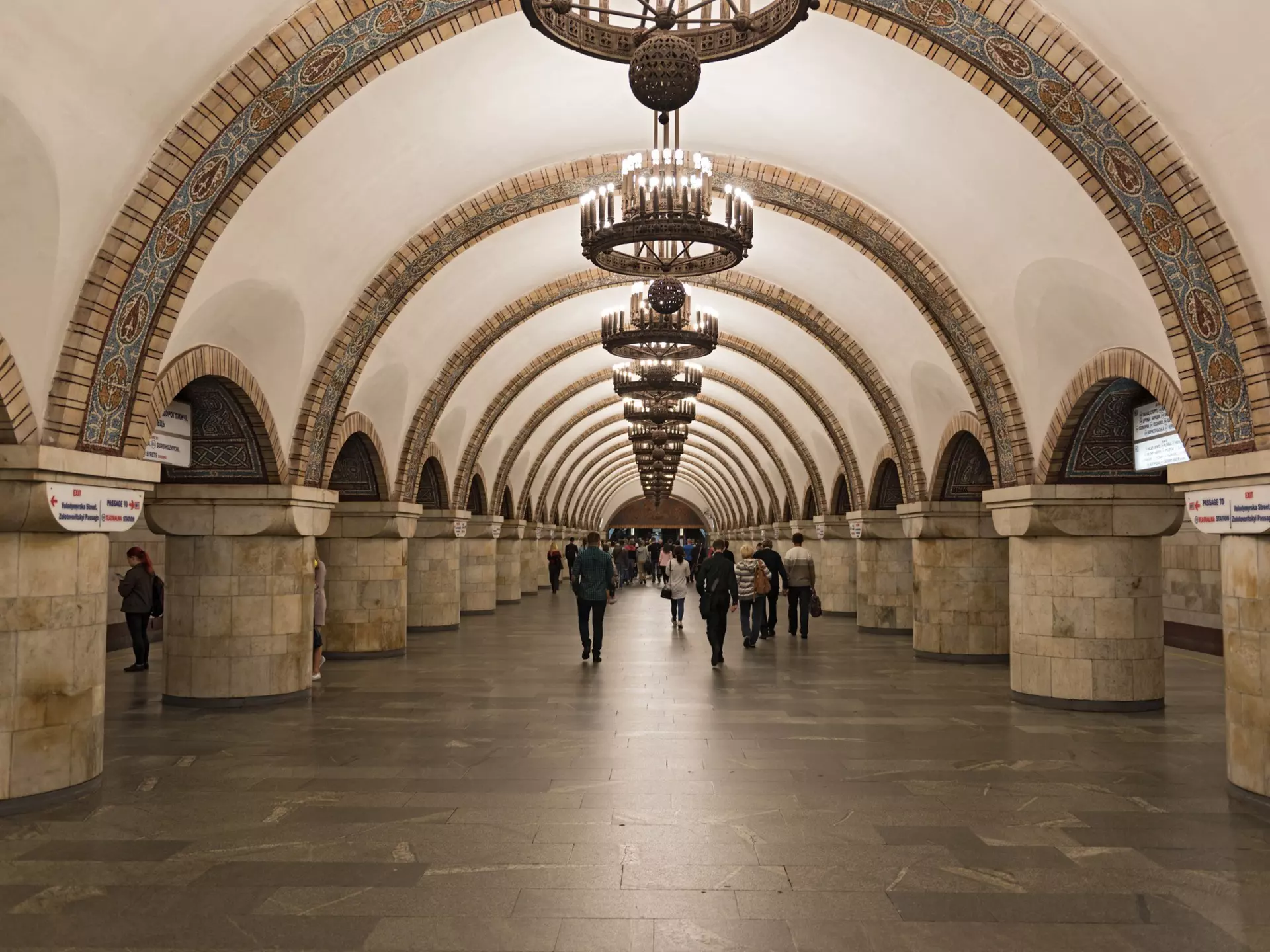 A long wide corridor with a vaulted ceiling and ornate chandeliers hanging down in Aresnalna, Kiev