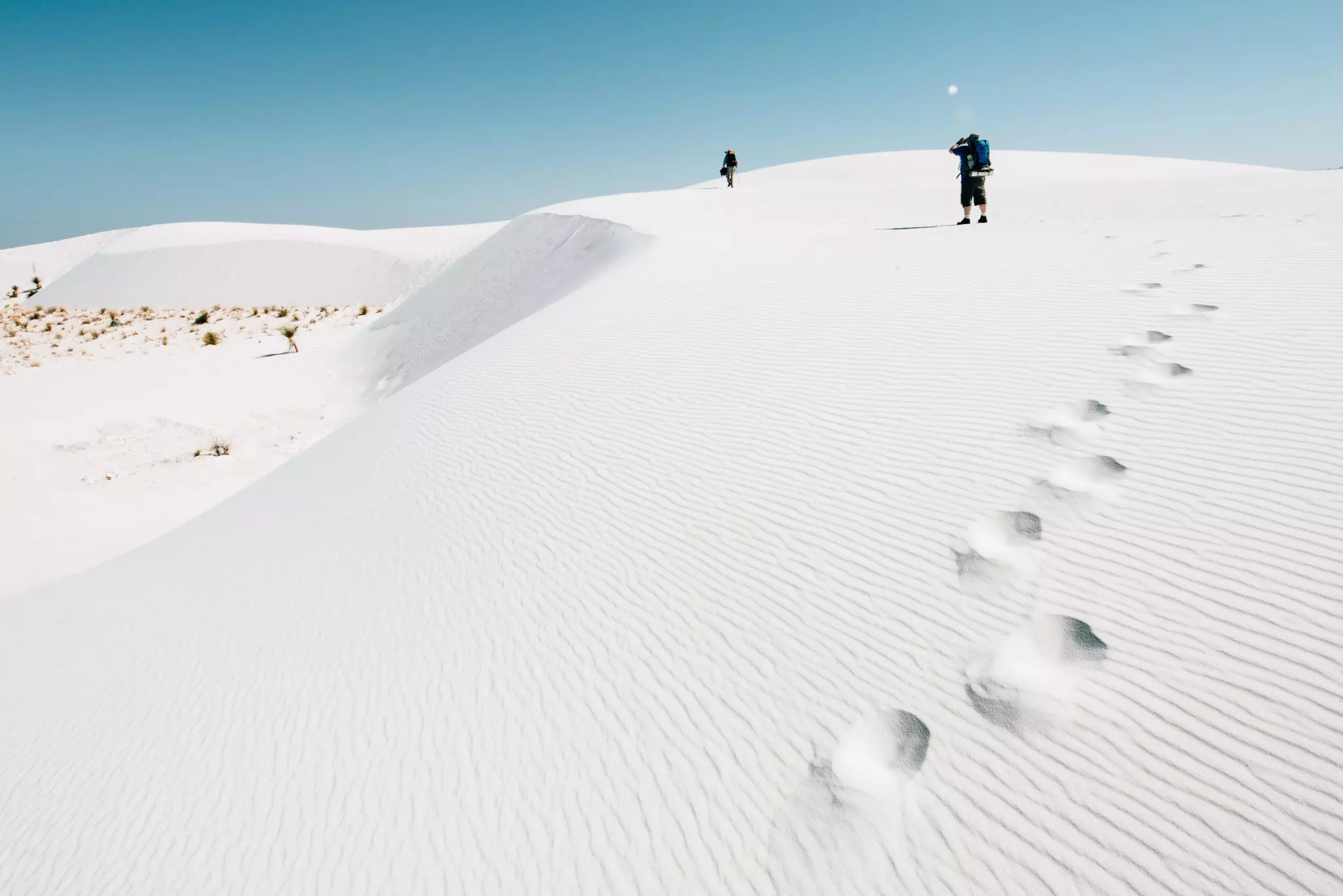 Backpackers hiking on sand dunes at White Sands National Monument.