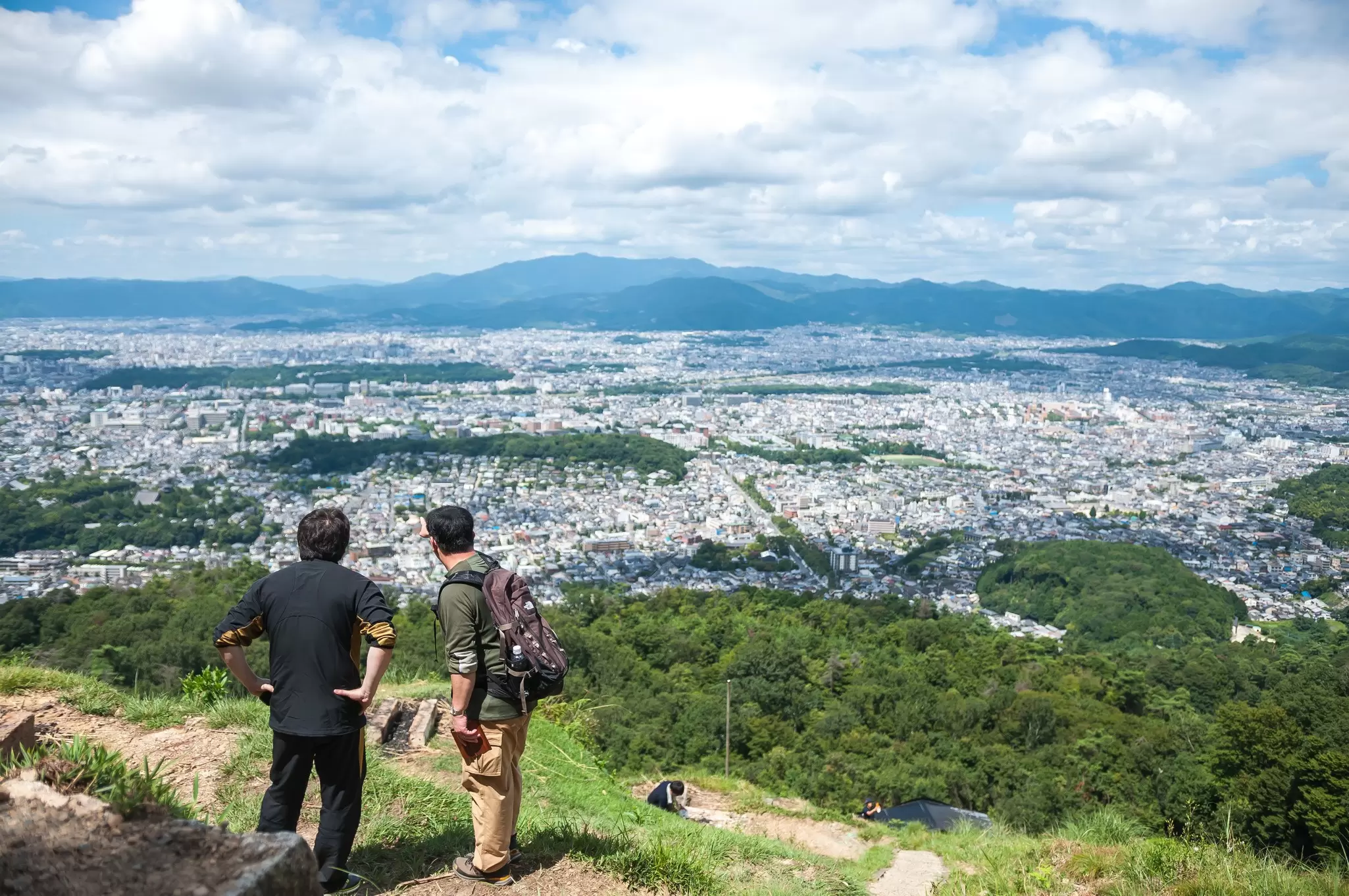 Two men looking at Kyoto Imperial Palace (which is situated in a rectangular enclosure) in Kyoto city, as seen from the peak of Daimonjiyama, Japan.