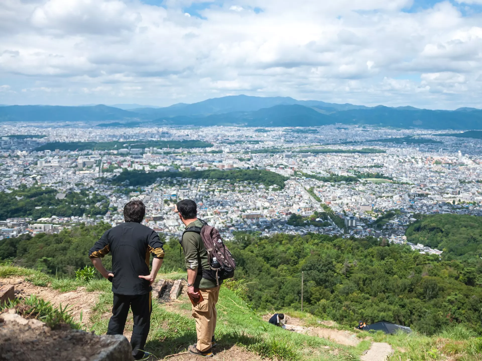 Two men looking at Kyoto Imperial Palace (which is situated in a rectangular enclosure) in Kyoto city, as seen from the peak of Daimonjiyama, Japan.