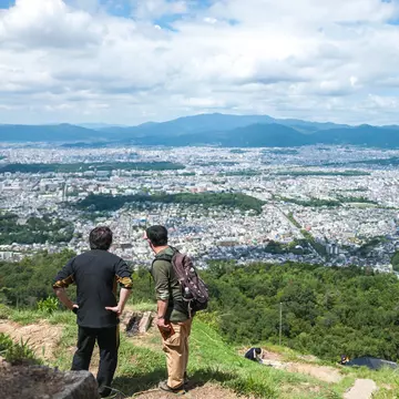Two men looking at Kyoto Imperial Palace (which is situated in a rectangular enclosure) in Kyoto city, as seen from the peak of Daimonjiyama, Japan.
