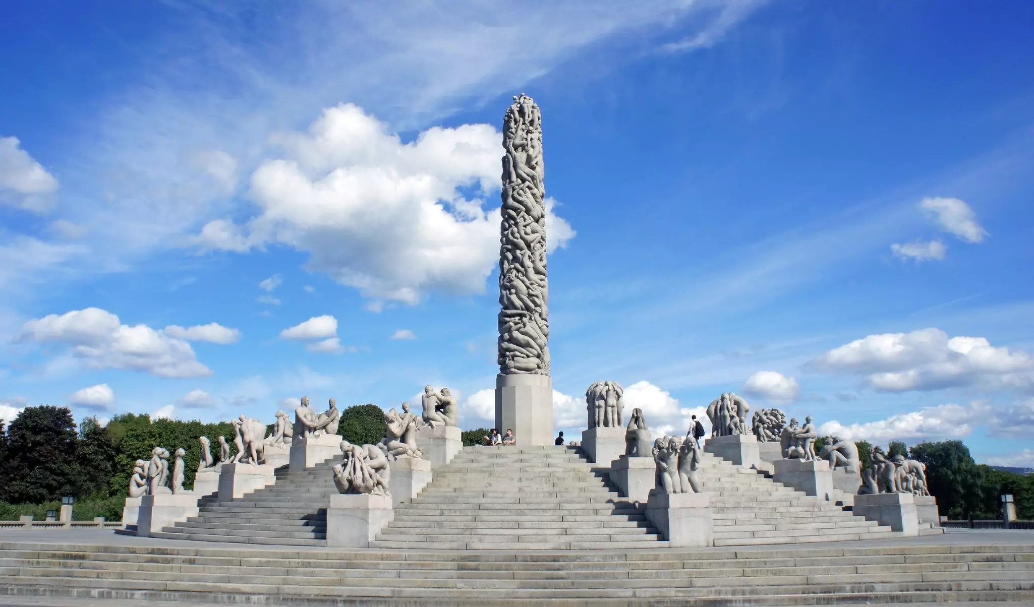 A central column of concrete figures overlapping surrounded by statues in a vast sculpture park.