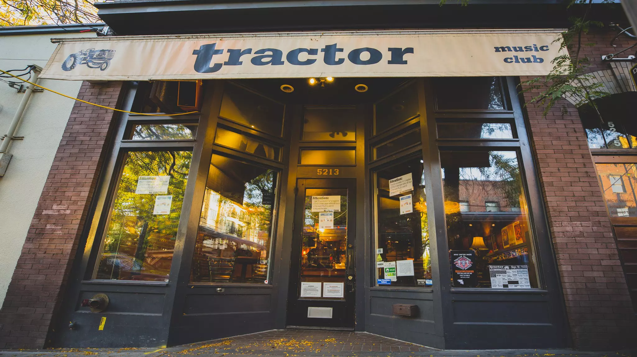 The exterior of a music club with the name "Tractor" on its beige awning.