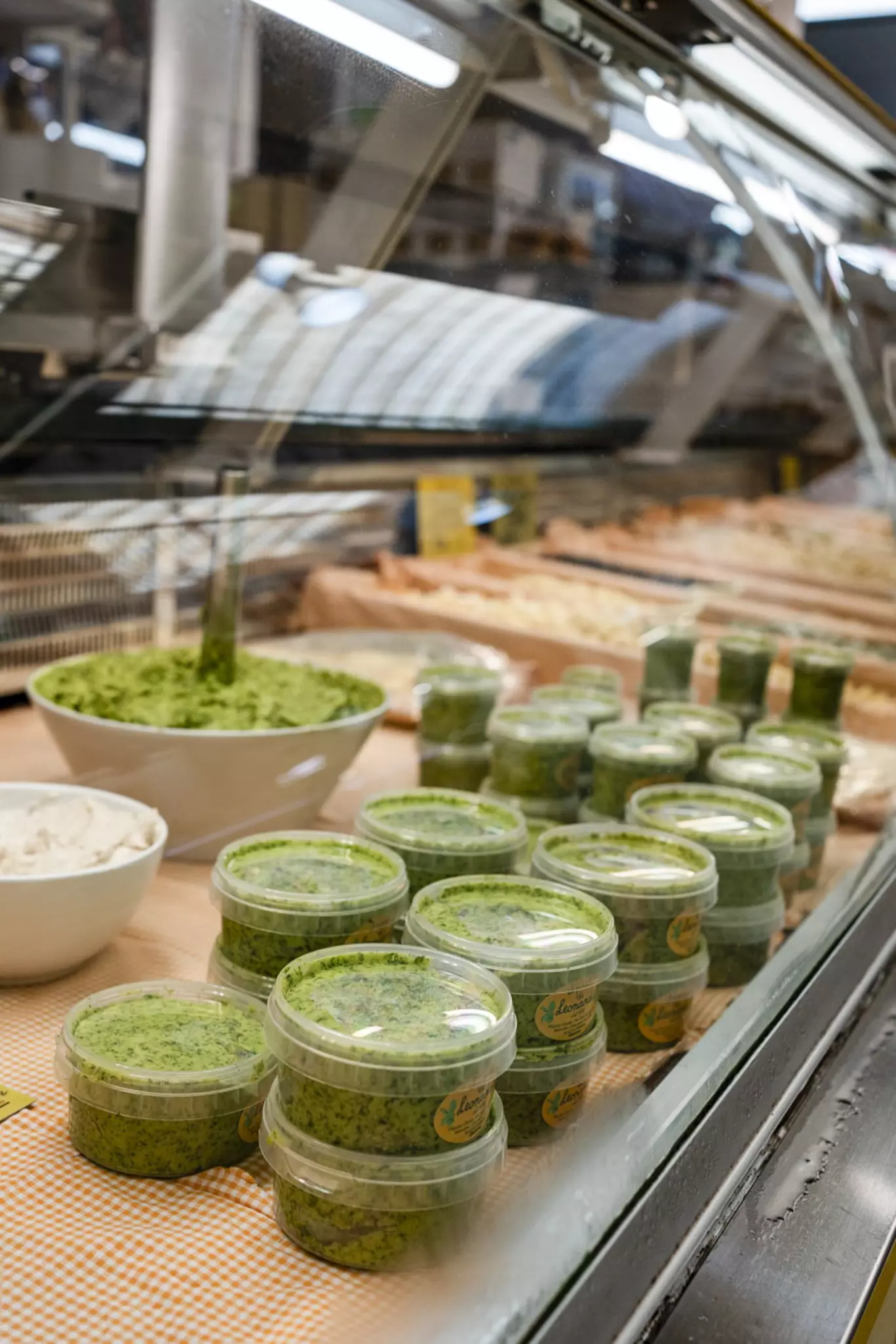Stacks of plastic containers filled with pesto on a shop counter