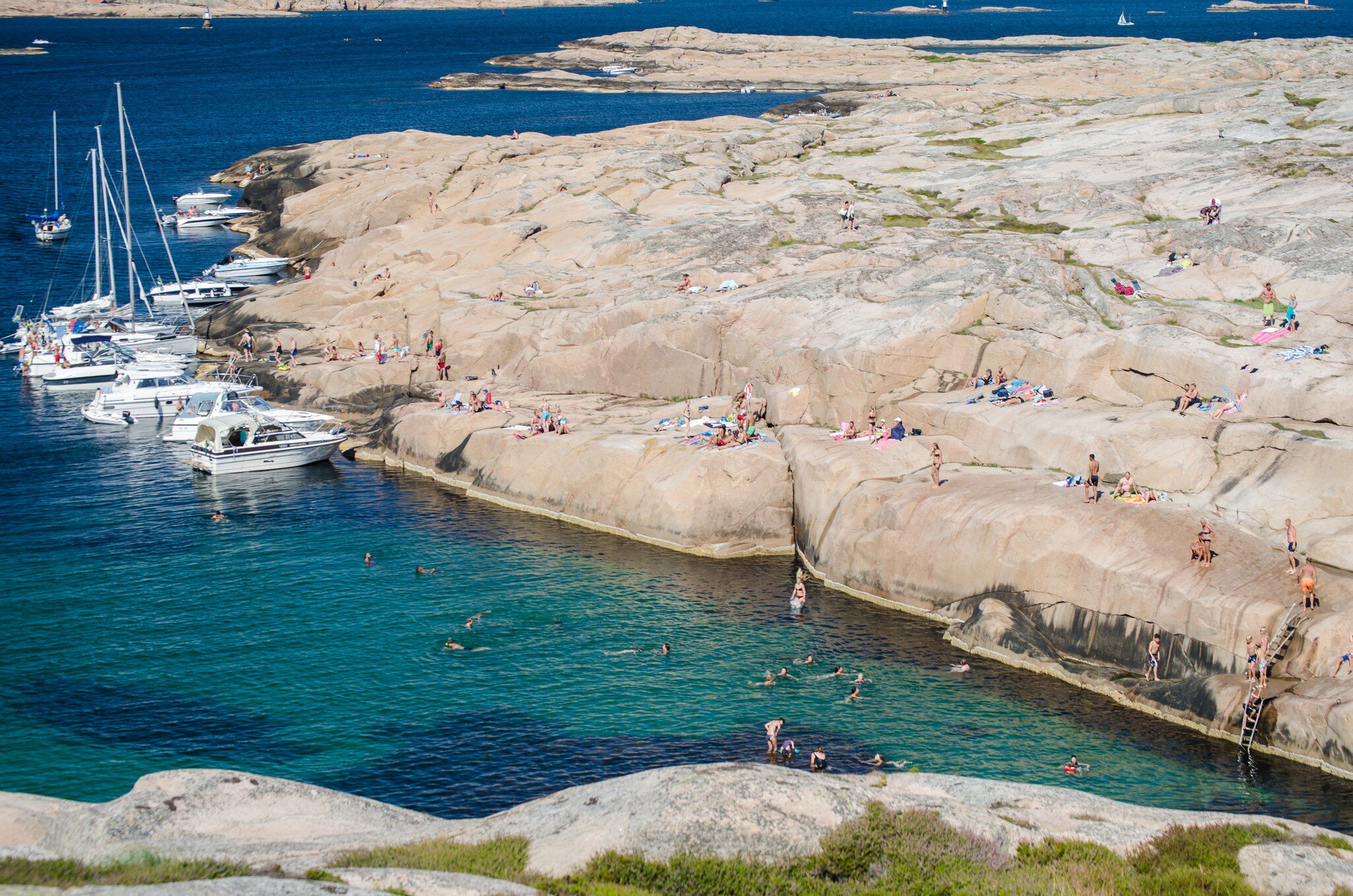 Hållö, Sweden, July 20, 2014. Boats at a natural harbor and people sunbathing at the cliffs in Sweden. The water in the lagoon is beautiful blue green. Copy space and place for text., License Type: media, Download Time: 2026-06-04T18:58:11.000Z, User: LP_NZhan, Editorial: true, purchase_order: 65050 - Digital Destinations and Articles, job: App Content, client: Lonely Planet App, other: Nadine Zhan