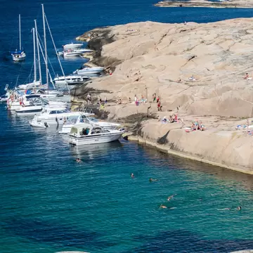 Hållö, Sweden, July 20, 2014. Boats at a natural harbor and people sunbathing at the cliffs in Sweden. The water in the lagoon is beautiful blue green. Copy space and place for text., License Type: media, Download Time: 2026-06-04T18:58:11.000Z, User: LP_NZhan, Editorial: true, purchase_order: 65050 - Digital Destinations and Articles, job: App Content, client: Lonely Planet App, other: Nadine Zhan