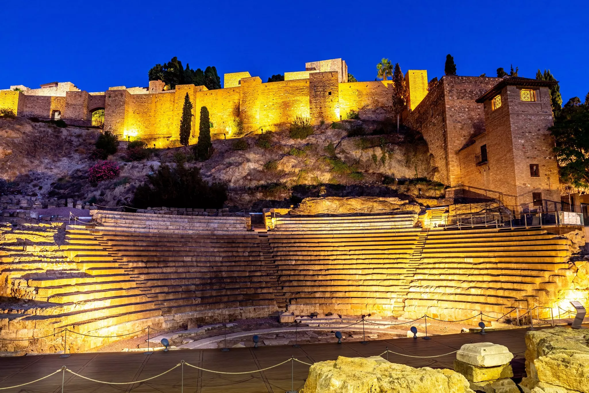 An ancient amphitheater is illuminated at dusk.