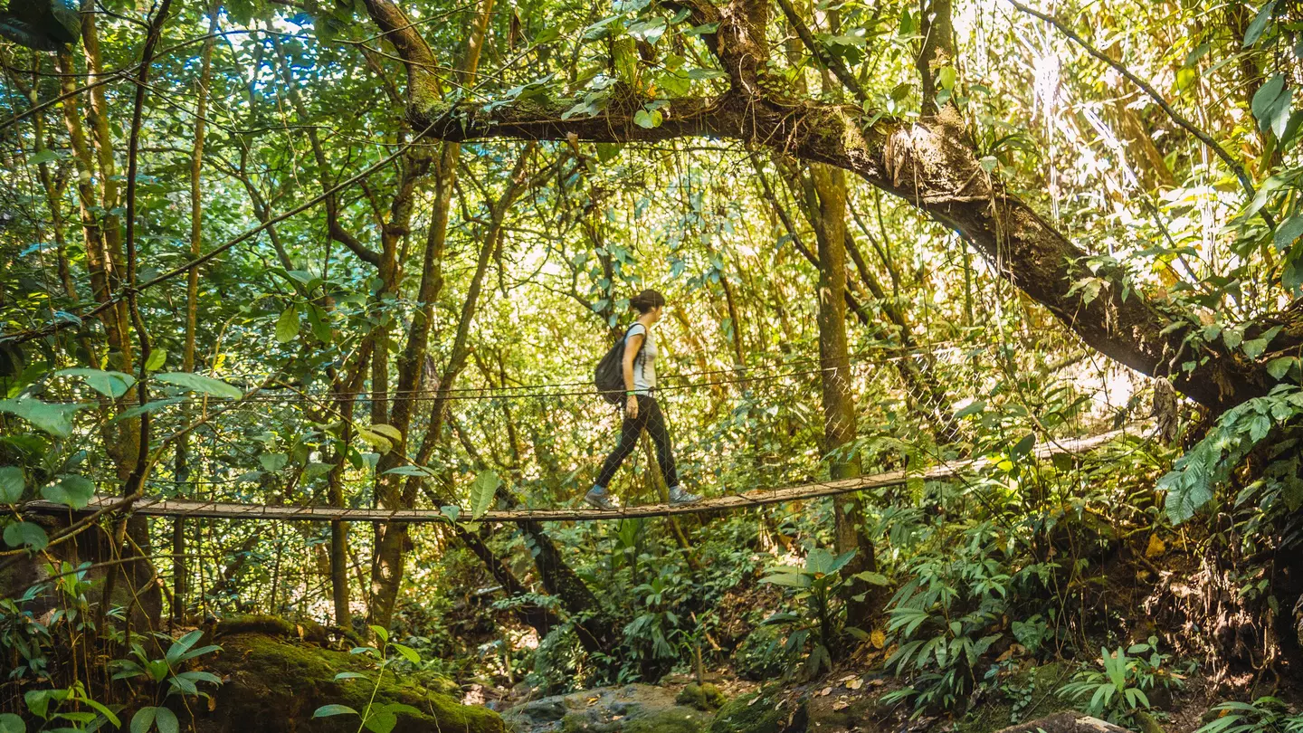 A young woman on a wooden bridge in the Cerro Azul Meámbar National Park, Yojoa, Honduras
