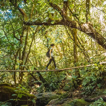 A young woman on a wooden bridge in the Cerro Azul Meámbar National Park, Yojoa, Honduras