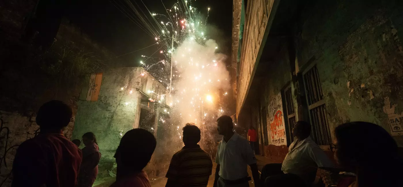People watch as firecrackers ignite an alley