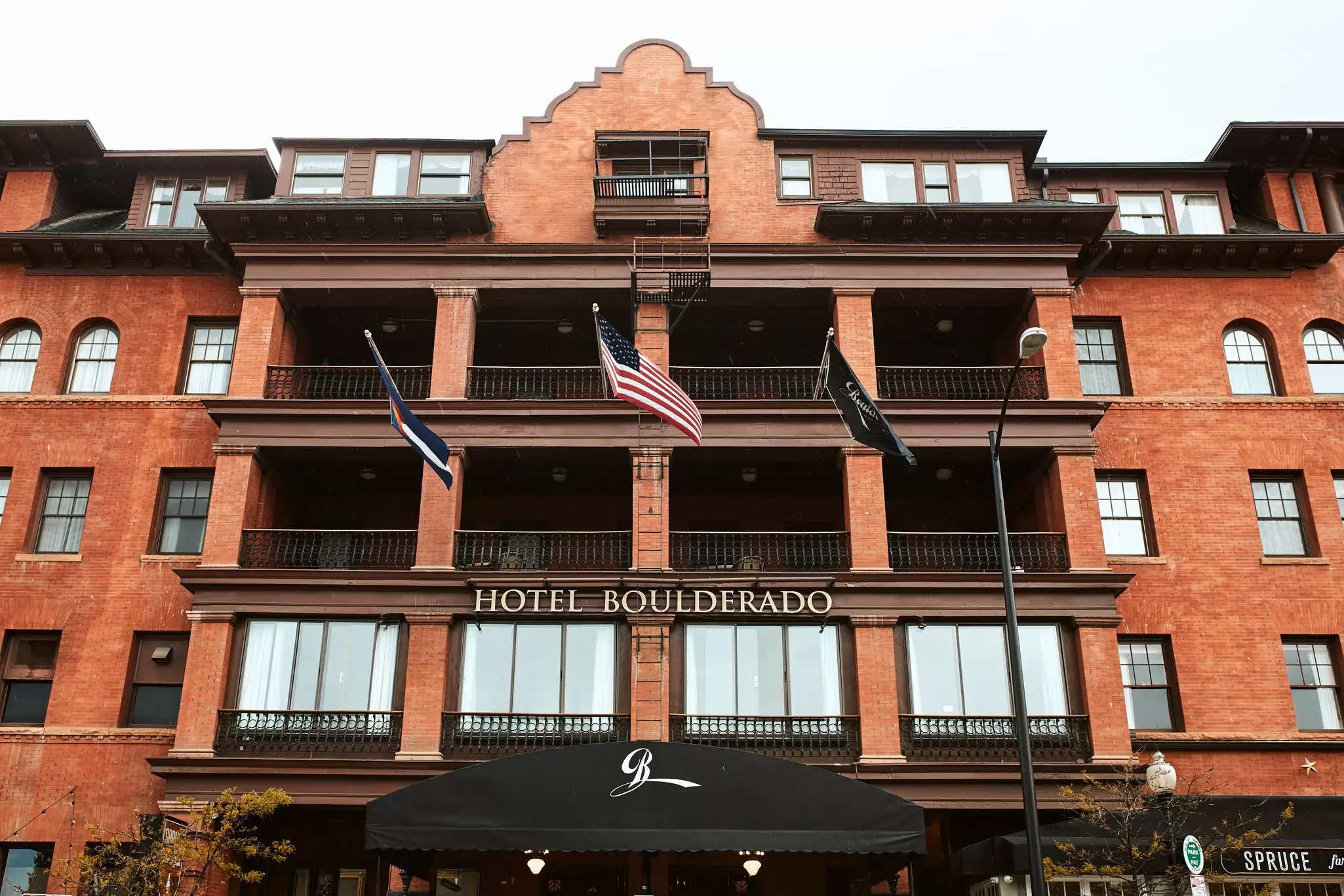 The exterior of a hotel with a USA flag flying near the balcony. Hotel Boulderado, Boulder