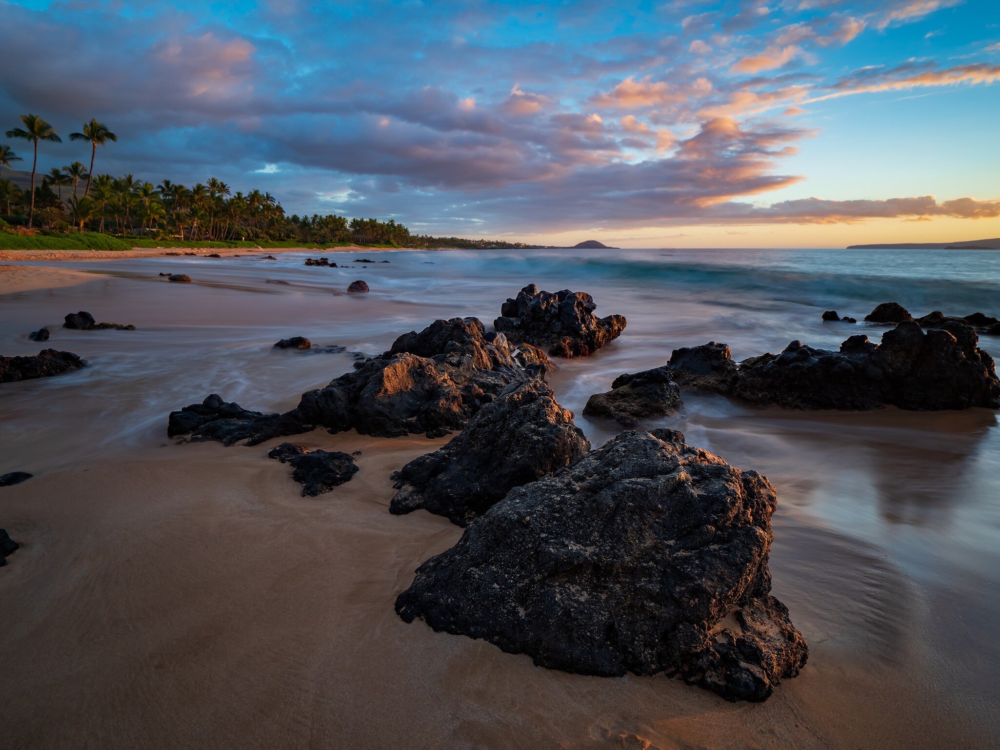 Keawakapu Beach on Maui at sunset with lava rocks in foreground.