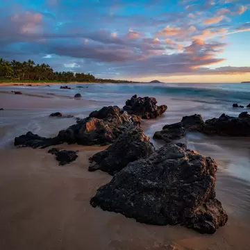 Keawakapu Beach on Maui at sunset with lava rocks in foreground.