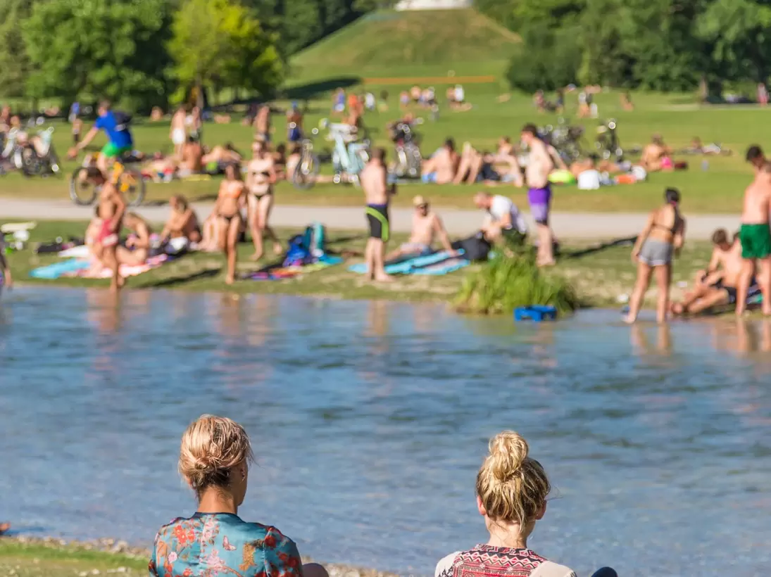 People enjoying the summer, sunbathing, swimming in Isar River in the Englischer Garten in Munich, Germany.