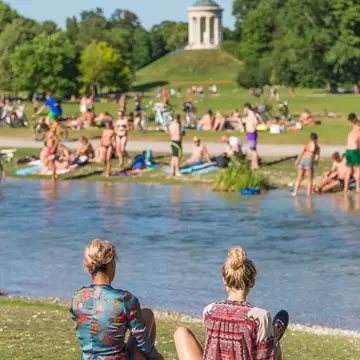 People enjoying the summer, sunbathing, swimming in Isar River in the Englischer Garten in Munich, Germany.