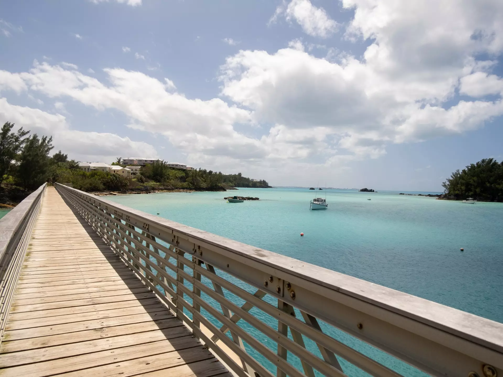 A walkway with a railing by a turquoise body of water.