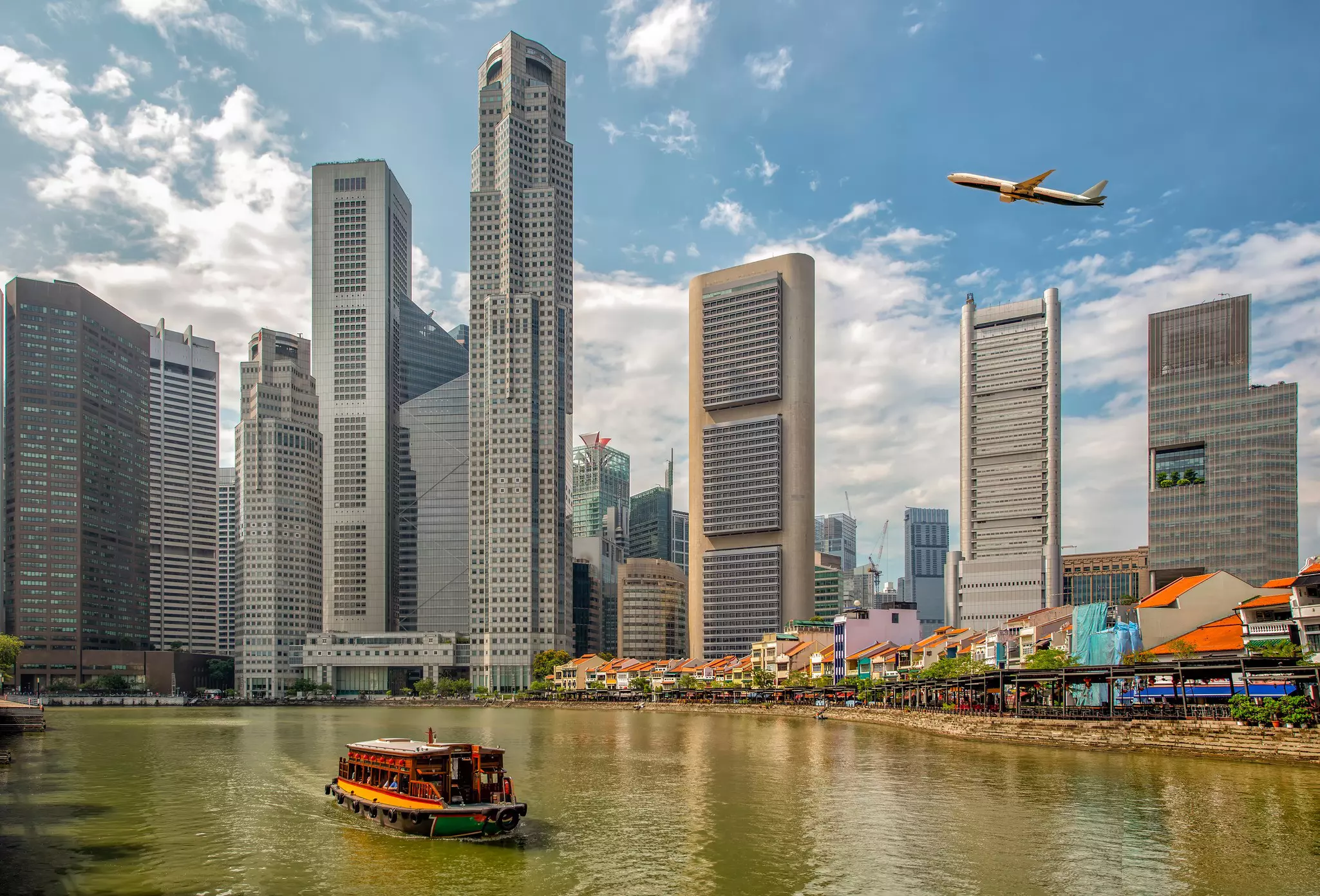 A plane takes off over a city by a quay