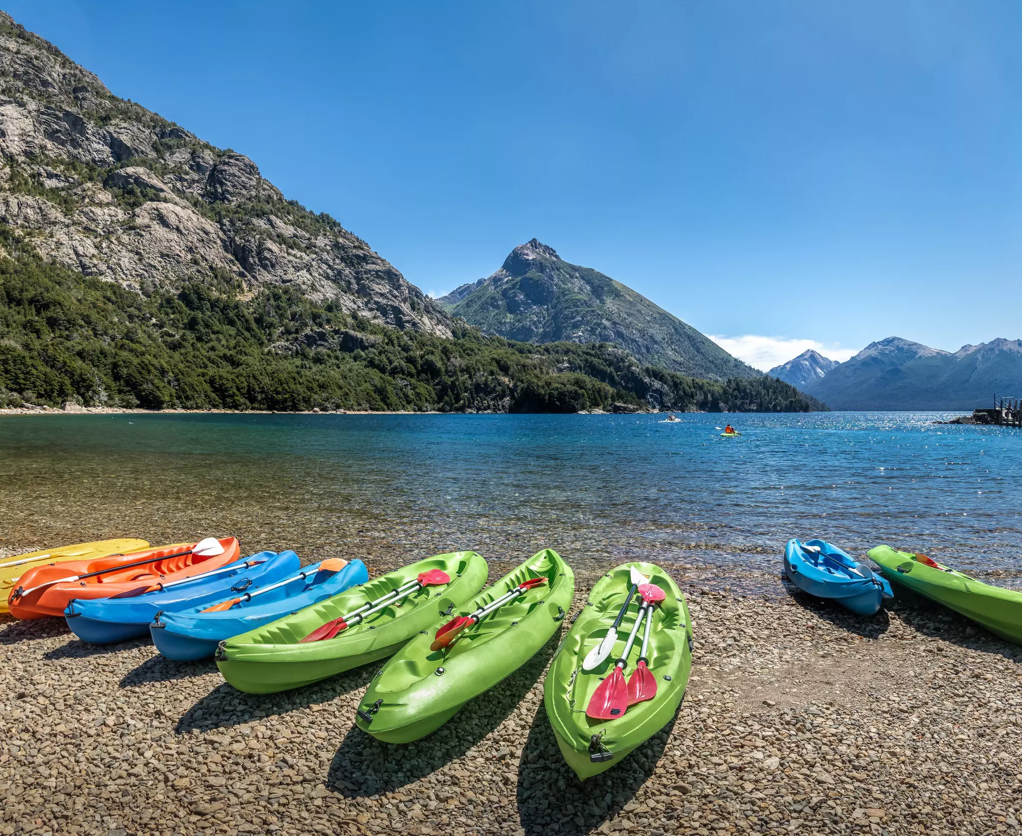 Colorful Kayaks in a lake surrounded by mountains at Bahia Lopez in Circuito Chico in Bariloche, Patagonia, Argentina.