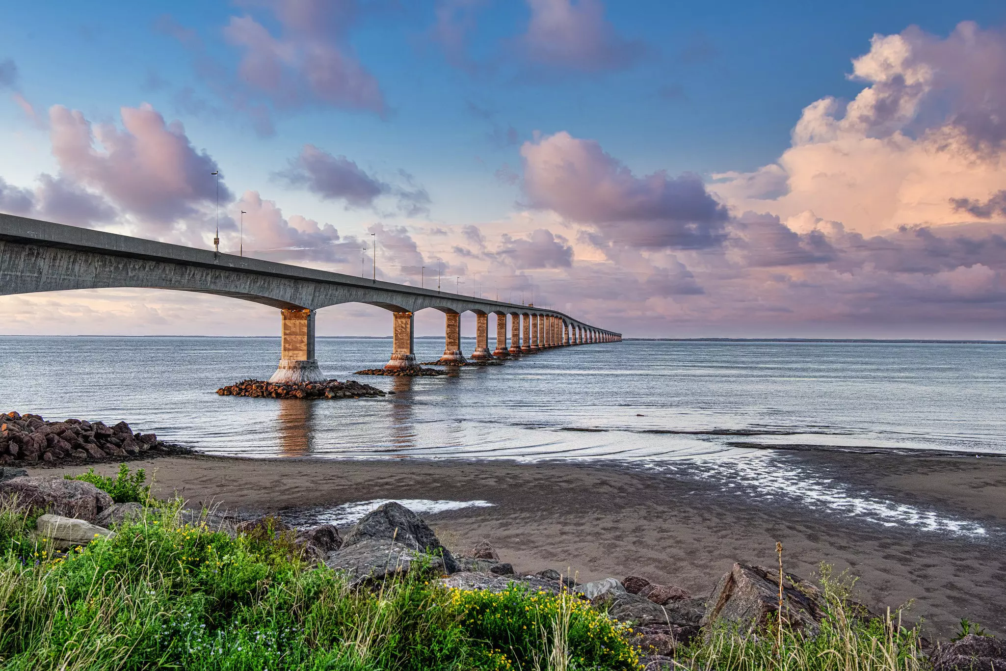 A large long stone bridge heads out across a body of water.