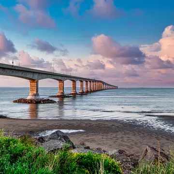 A large long stone bridge heads out across a body of water.