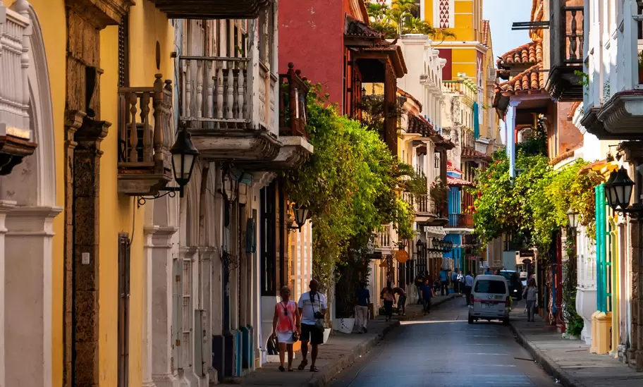 A yellow tower against blue sky at the end of a narrow street in a town's historic center.