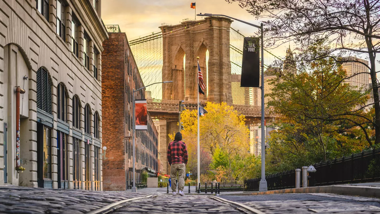 Man walking in Brooklyn admiring the Brooklyn Bridge at sunset, New York City