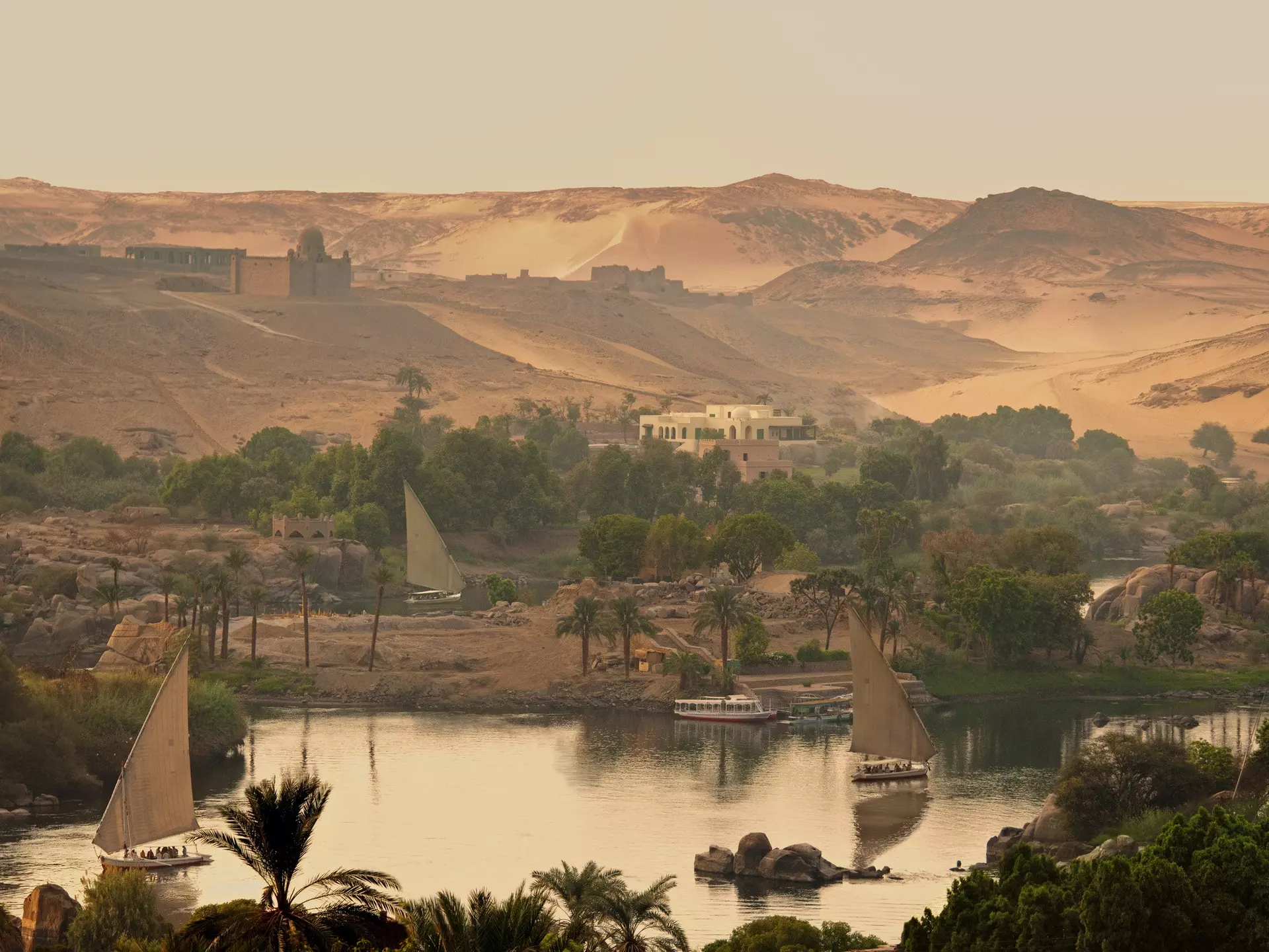 Felucca boats sailing on the Nile River. The Aga Khan’s domed mausoleum sits on the hill in the background. ©Peter Seaward/Lonely Planet