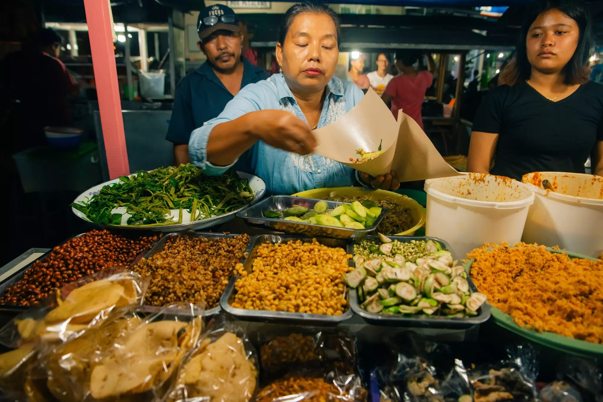 A woman offers snacks for sale at a market stall in Ubud, Bali, Indonesia.