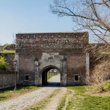 A brick and stone fortress gateway with an arched passage, below grassed ramparts.