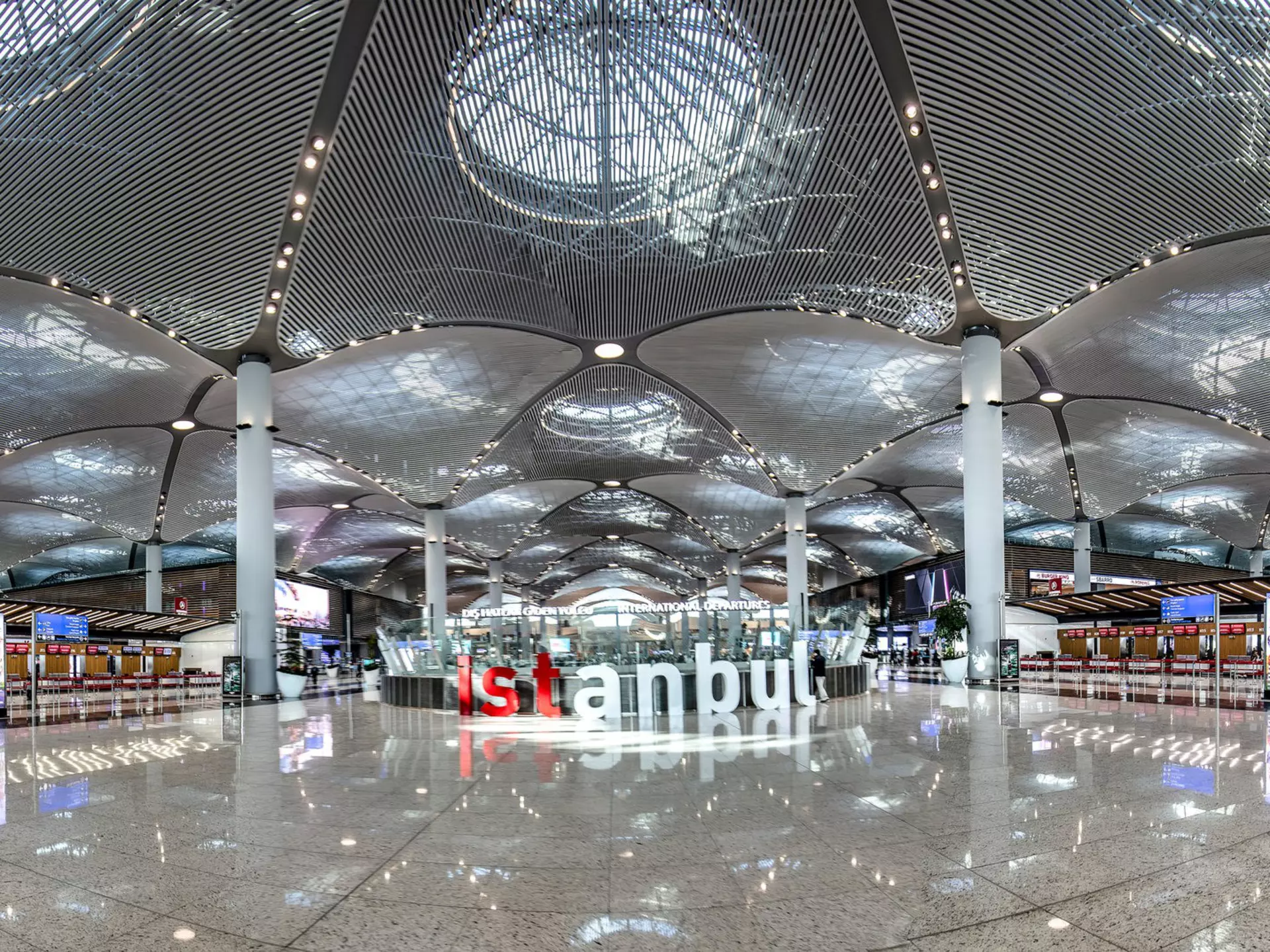 Brightly lit airport terminal with red and white letters that spell out Istanbul in the middle of the floor