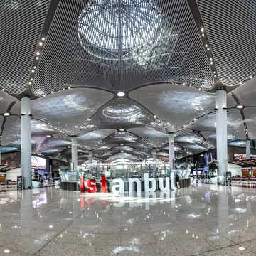 Brightly lit airport terminal with red and white letters that spell out Istanbul in the middle of the floor