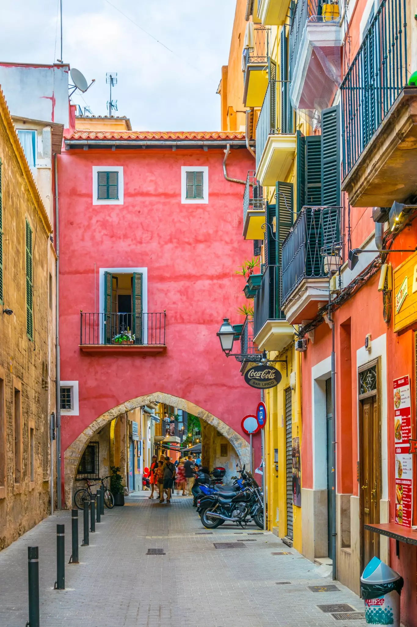 A pink archway between a street lined with brightly colored buildings.