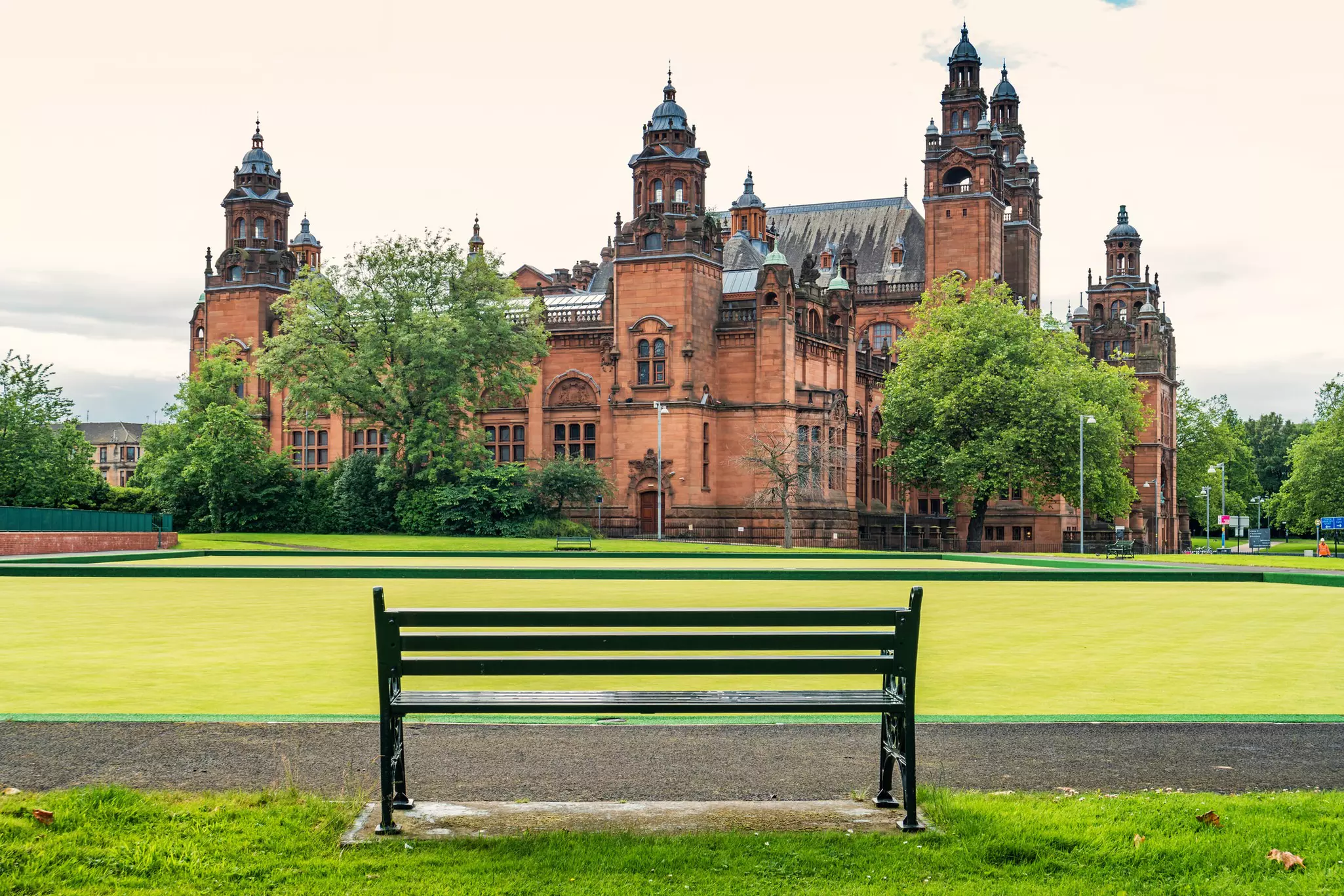 Empty bench with the Kelvingrove Art Gallery & Museum in the background, Glasgow, Scotland.