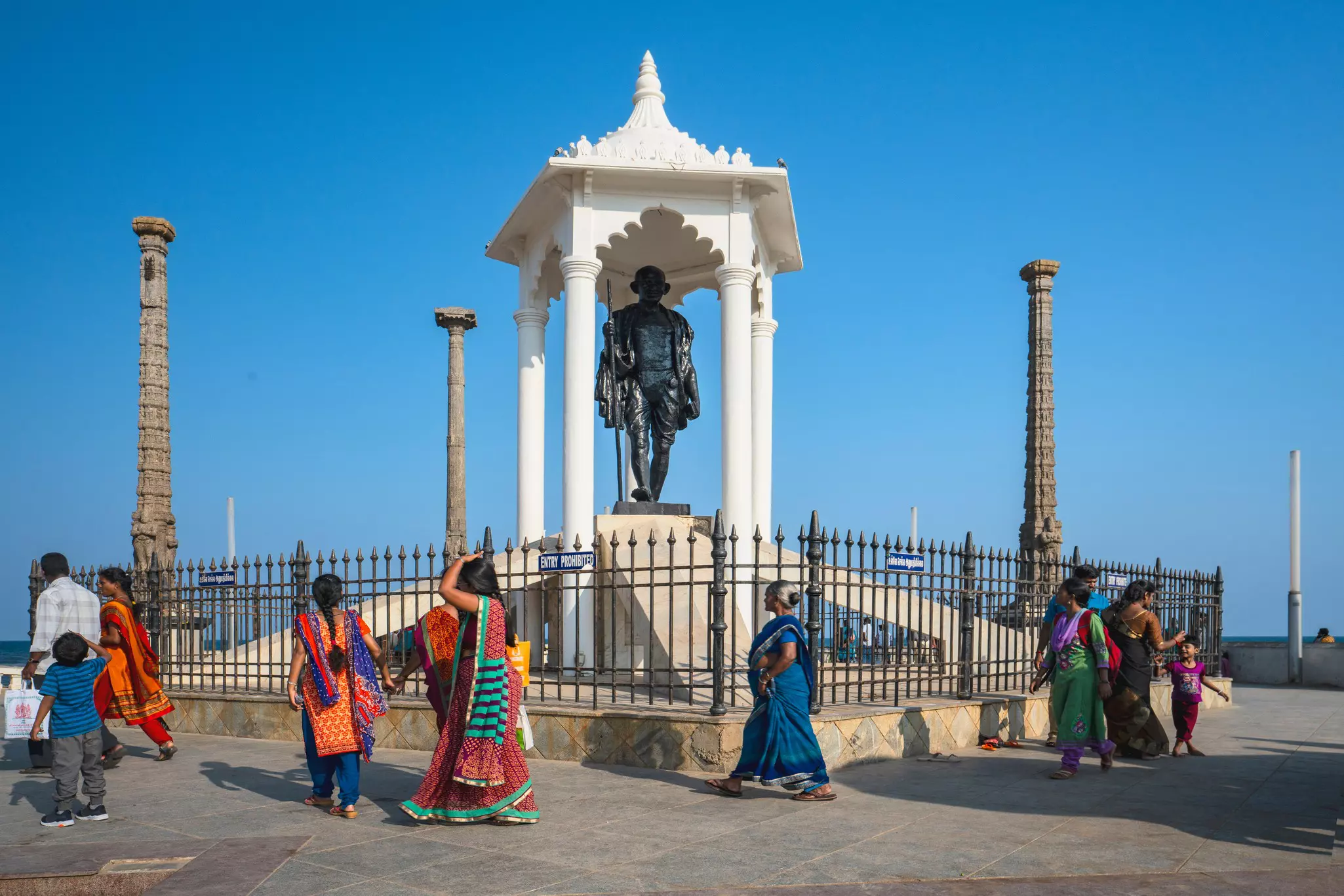 People walk by the Gandhi Memorial on at the promenade beach front, Puducherry, India