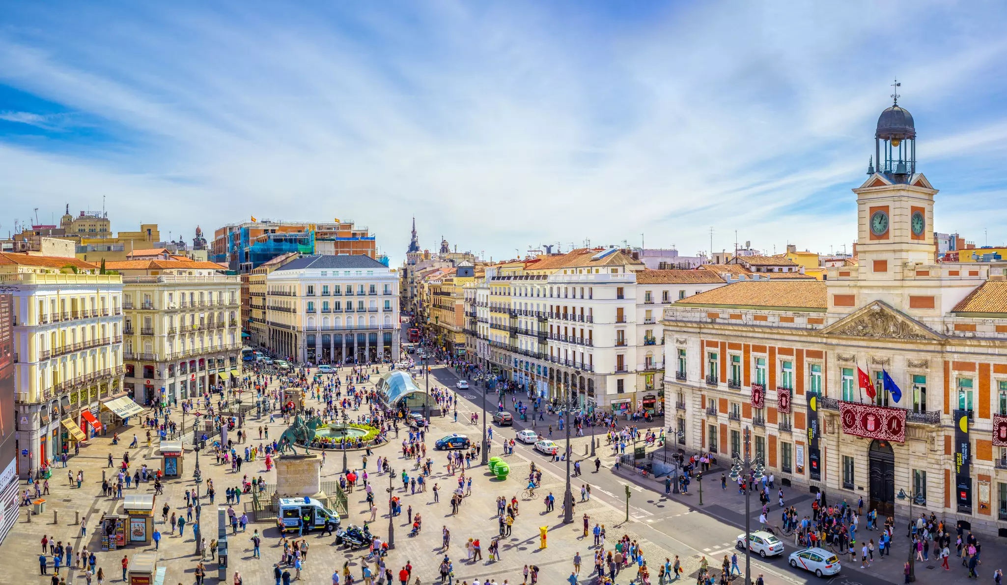 An overhead view of a huge city square surrounded by historic buildings and filled with hundreds of people.