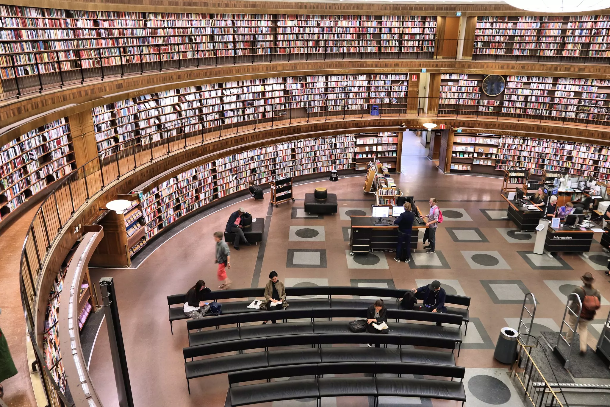 People in a round reading room with books filling the curved shelves