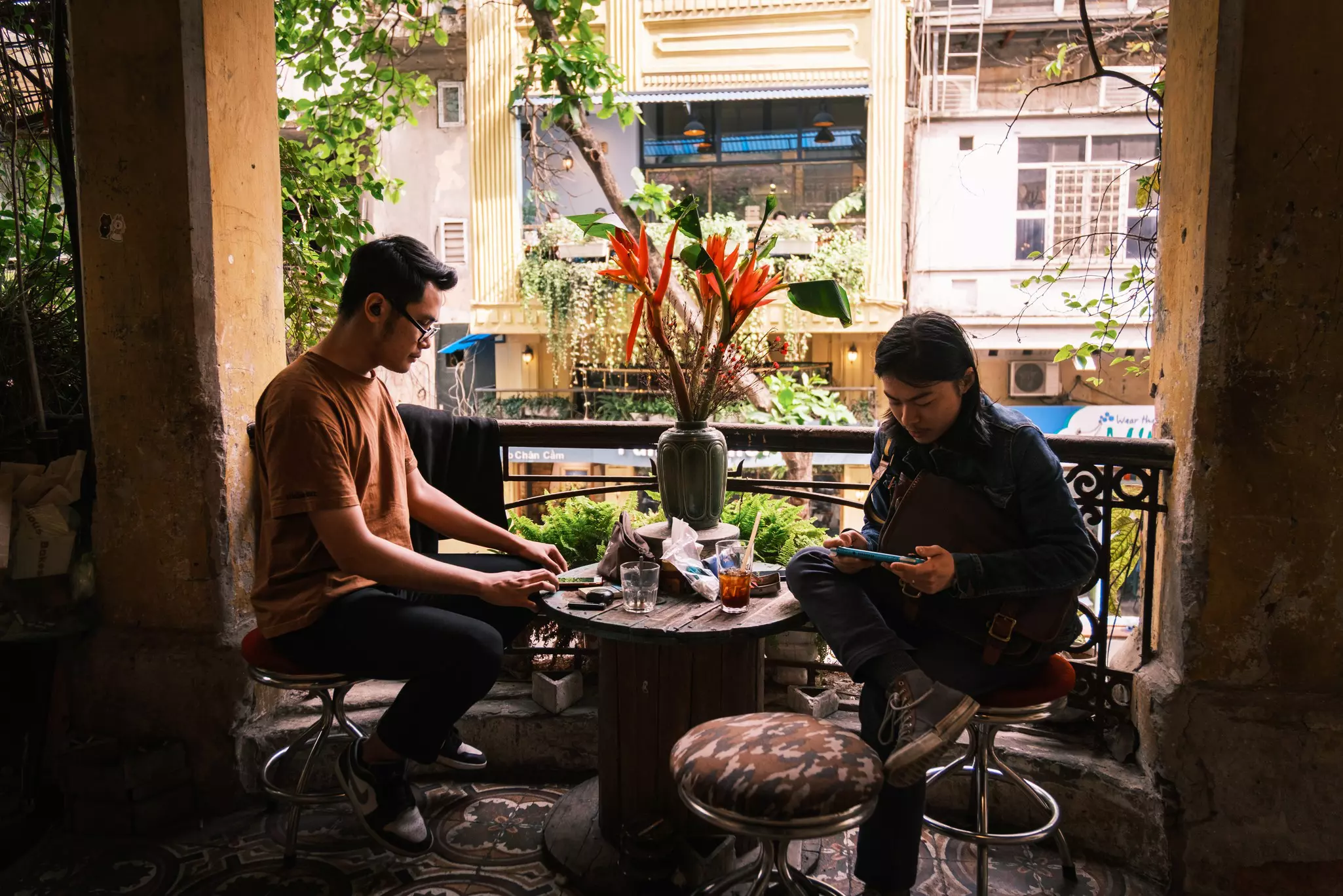 Two people sit at table on balcony as they enjoy drinks from Loading T Cafe.