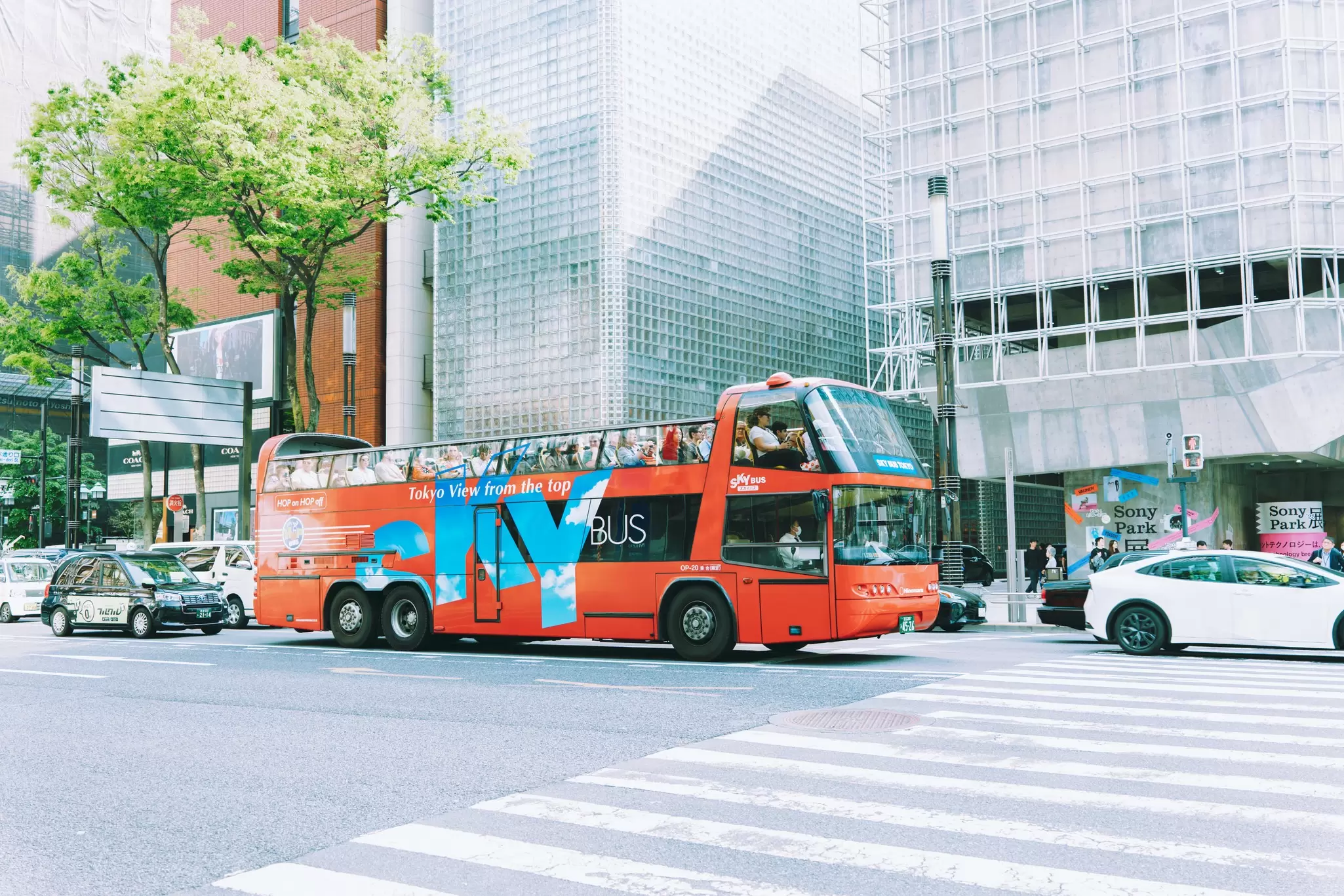 A red double-decker bus approaches a crosswalk.