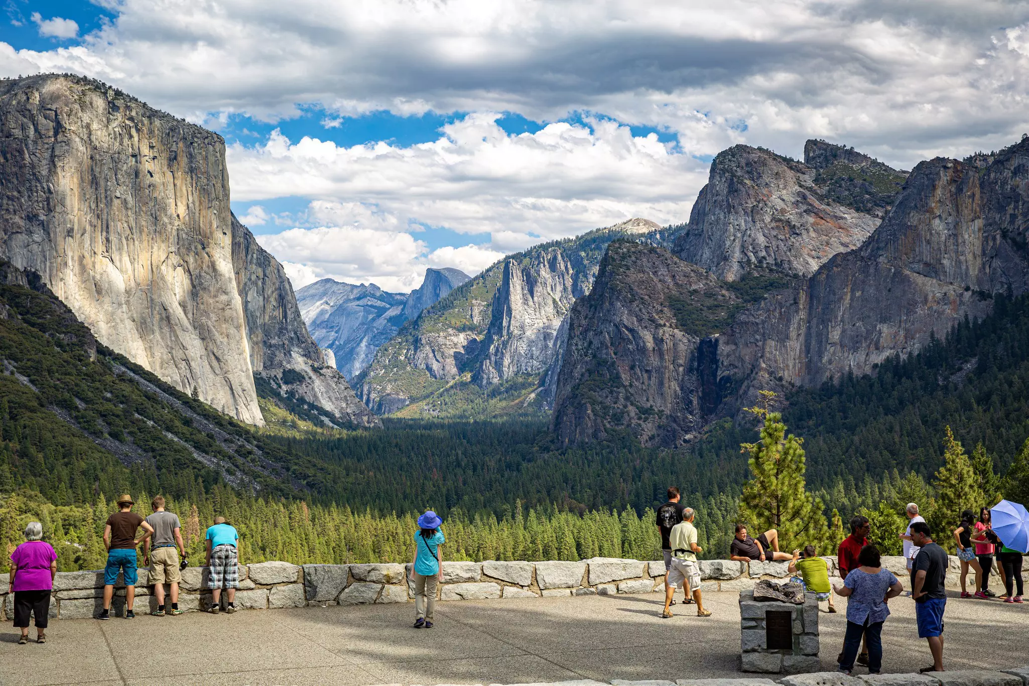 Tourists taking pictures in Yosemite Nation Park on a scenic roadside pull off, Tunnel View. El Capitan, Half Dome, and Bridalveil Fall are all visible. © Getty Images