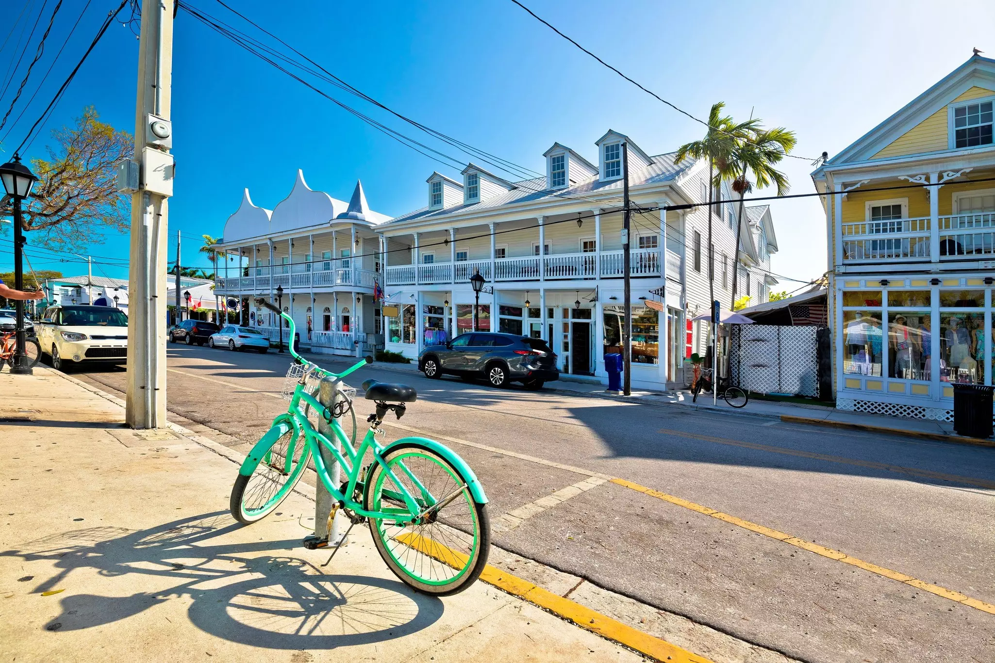 A green bicycle is parked by white houses on Duval St, Key West